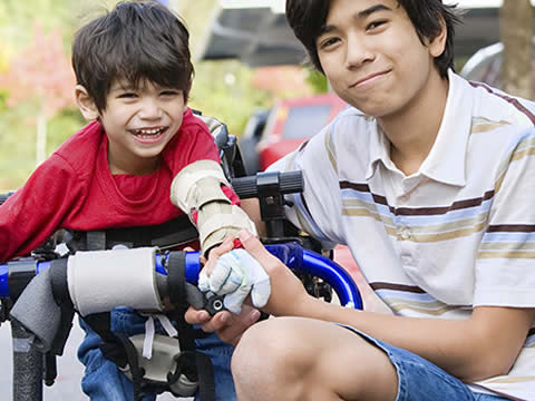 Older brother with younger brother who is in an assistive walker. Image courtesy of SCATP.